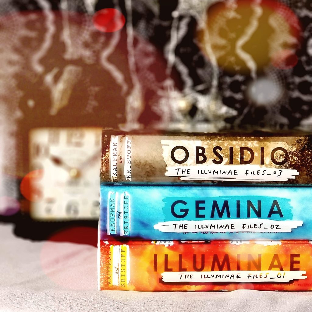 Stack of three The Illuminae Files young adult trilogy books with a clock in the background and color spots filter