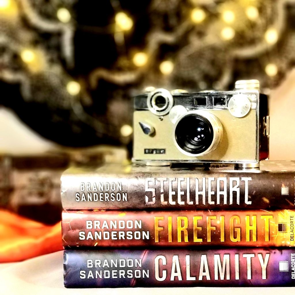 Stack of all three The Reckoners young adult trilogy books with old-fashioned camera sitting on top